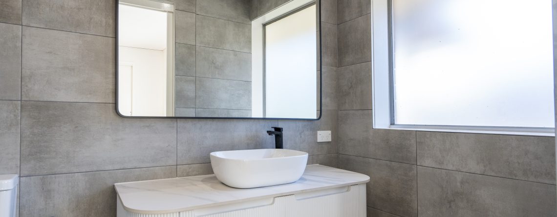 Bathroom with large stone tiles, white vanity and sink with a large mirror