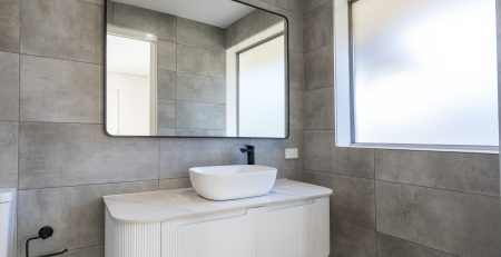 Bathroom with large stone tiles, white vanity and sink with a large mirror