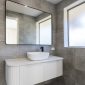 Bathroom with large stone tiles, white vanity and sink with a large mirror