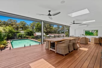 Spacious covered deck with dining area overlooking pool.