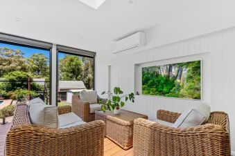 Covered outdoor lounge with wicker seating and garden view.