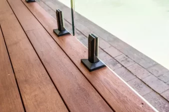 Timber deck with glass pool fence and black metal posts.