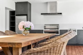Outdoor kitchen with barbecue and wooden dining table.