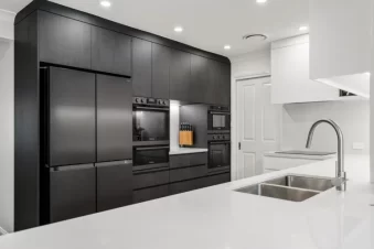 Modern kitchen with black cabinets and white island bench.